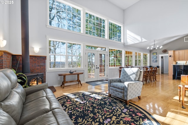 living area with french doors, light wood finished floors, plenty of natural light, and a wood stove