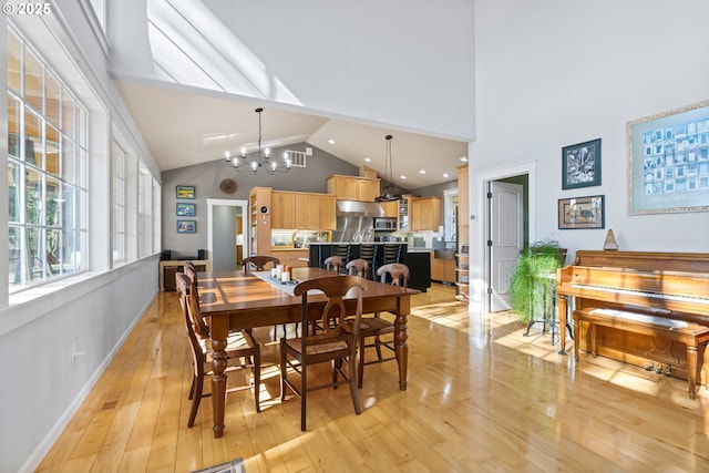 dining space featuring high vaulted ceiling, light wood-style flooring, a chandelier, and baseboards