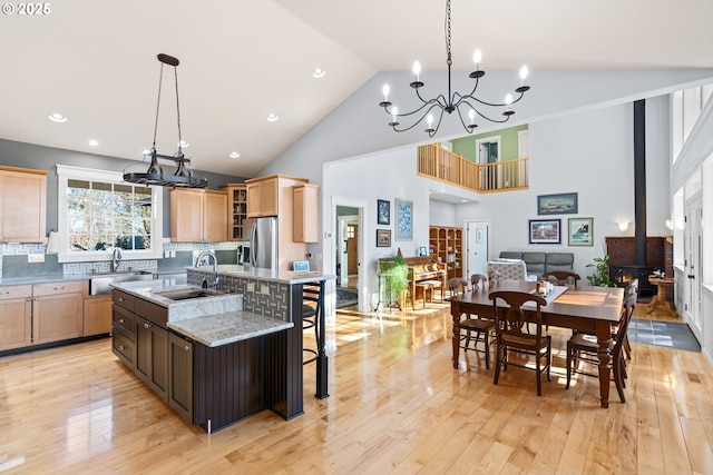 kitchen featuring a wood stove, an island with sink, a sink, and freestanding refrigerator