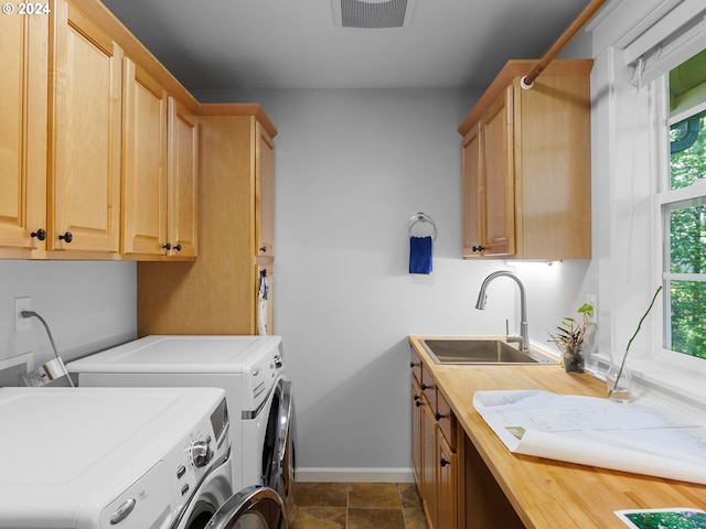 clothes washing area featuring a sink, visible vents, baseboards, washer and dryer, and cabinet space