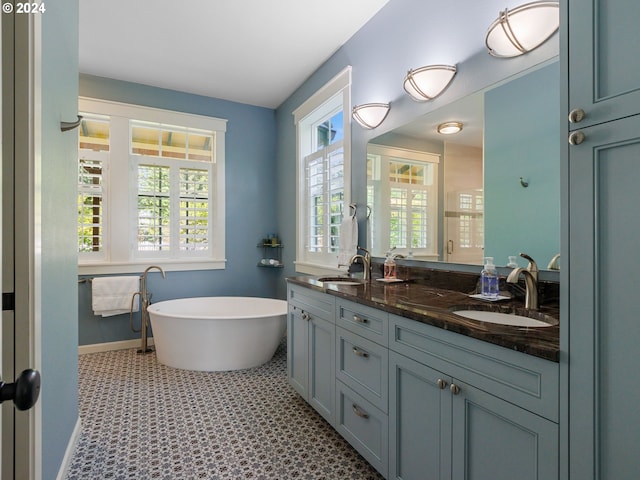 full bath with baseboards, a sink, a freestanding bath, and double vanity