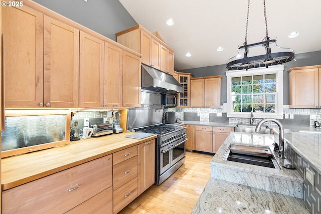 kitchen with under cabinet range hood, stainless steel appliances, backsplash, and light brown cabinetry