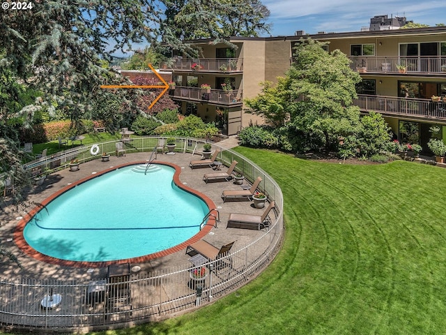 pool with a patio area and a lawn