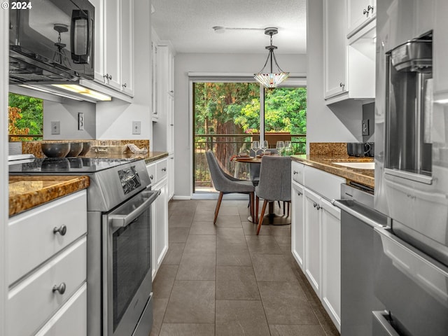 kitchen with dark tile patterned flooring, dark countertops, appliances with stainless steel finishes, a textured ceiling, and white cabinetry