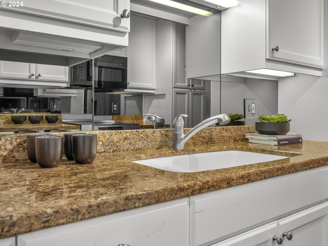 interior space with black microwave, white cabinets, and a sink