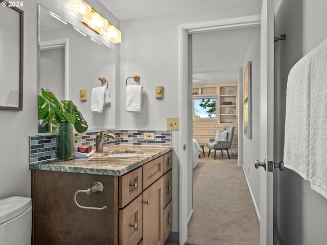 ensuite bathroom featuring baseboards, decorative backsplash, connected bathroom, toilet, and vanity