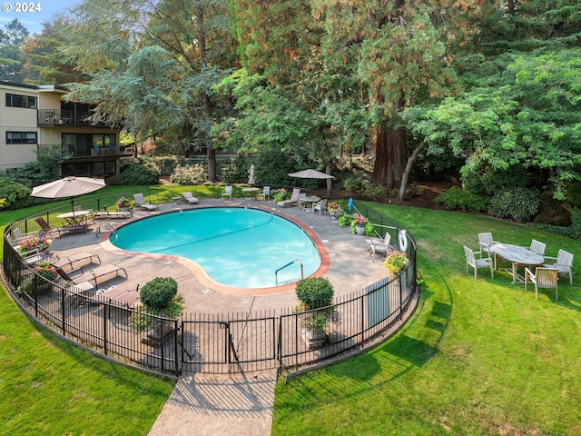 pool featuring a patio area, fence, and a lawn