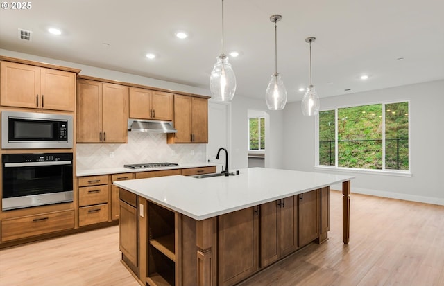 8710 S 3rd St, Ridgefield, WA 98642 - kitchen with appliances with stainless steel finishes, decorative backsplash, an island with sink, light countertops, and light wood-type flooring