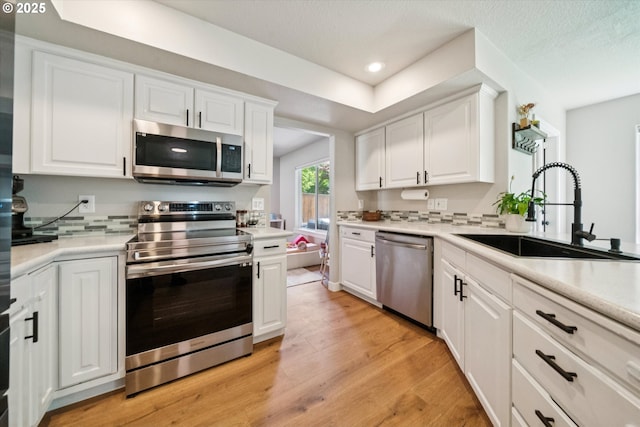 1686 NE 27th Ter, Gresham, OR 97030 - kitchen with appliances with stainless steel finishes, white cabinetry, light wood-style flooring, light countertops, and recessed lighting