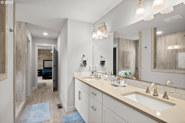 bathroom featuring tiled shower, visible vents, a sink, and wood finished floors