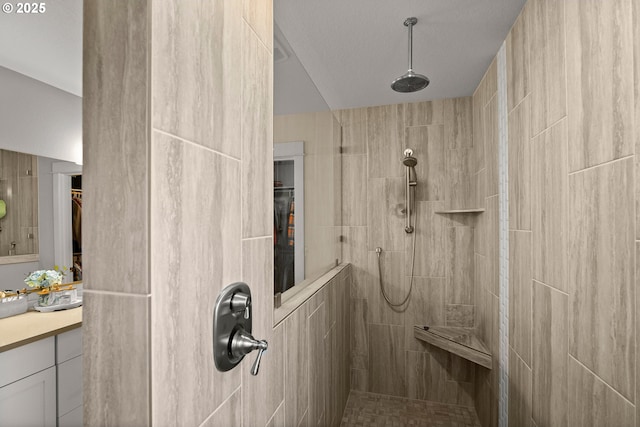 bathroom with a walk in shower, vanity, and a spacious closet