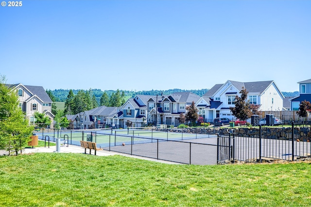 exterior space with a residential view, fence, a tennis court, and a yard