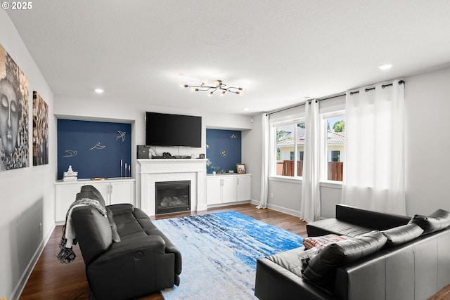 living room featuring recessed lighting, baseboards, a glass covered fireplace, and wood finished floors
