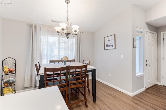 dining room with an inviting chandelier, hardwood / wood-style flooring, and vaulted ceiling