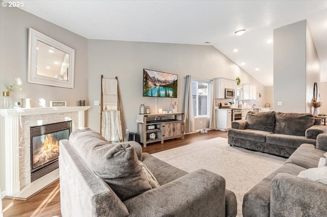 living room with vaulted ceiling, a premium fireplace, and light wood-type flooring