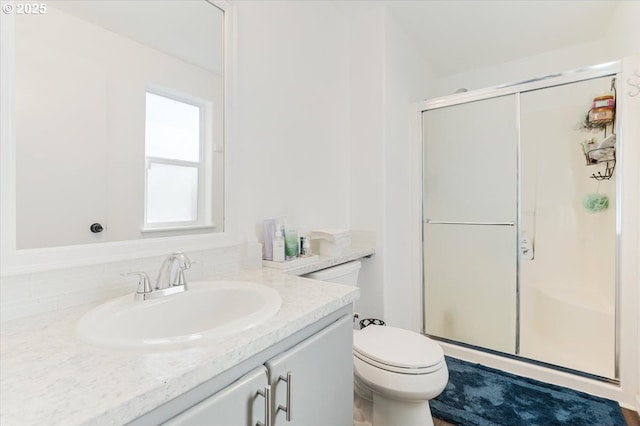 bathroom featuring vanity, a shower with shower door, and toilet