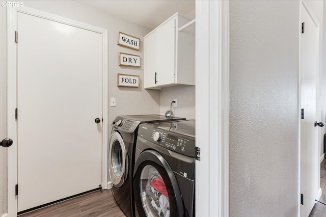 clothes washing area with cabinets, separate washer and dryer, and hardwood / wood-style floors