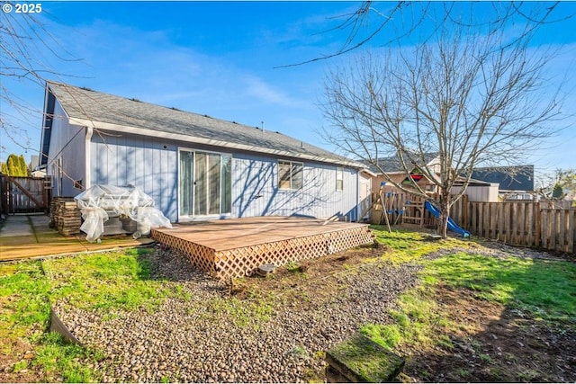 back of house featuring a playground and a wooden deck