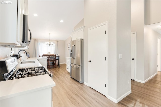 kitchen with white cabinetry, lofted ceiling, sink, hanging light fixtures, and stainless steel appliances