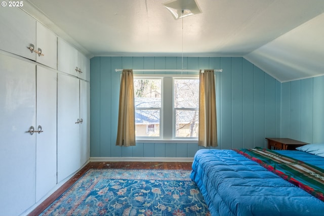 bedroom featuring lofted ceiling, wood finished floors, and baseboards