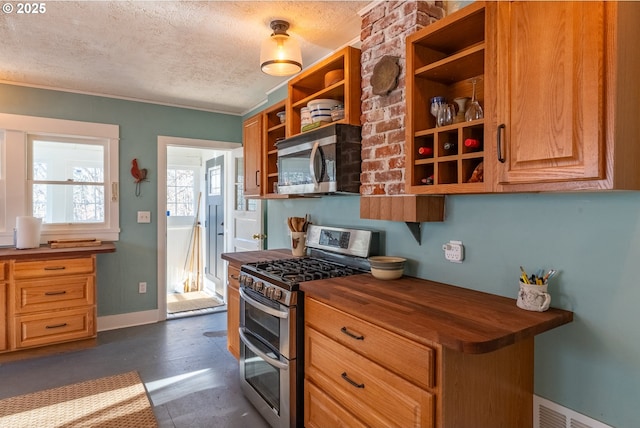 kitchen with open shelves, stainless steel appliances, visible vents, a textured ceiling, and butcher block countertops