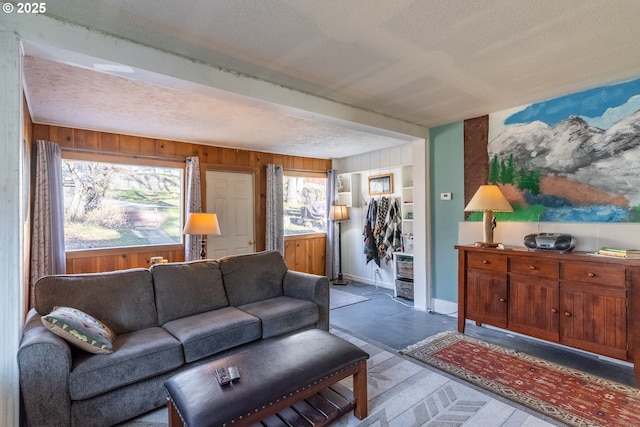 living room featuring a textured ceiling, baseboards, and wooden walls