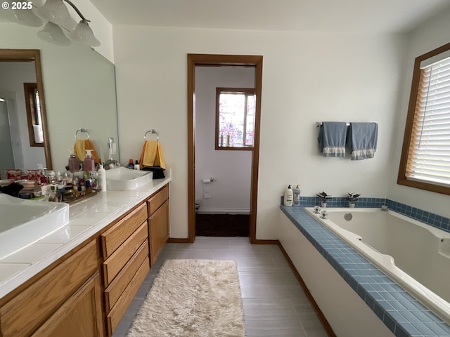 full bath featuring a garden tub, toilet, a sink, baseboards, and double vanity