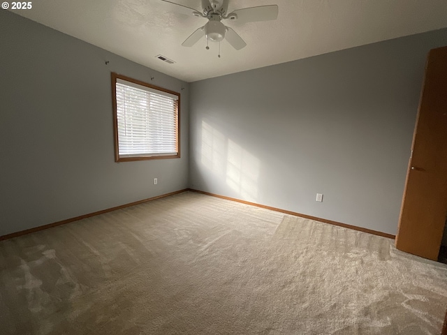 carpeted empty room with a textured ceiling, a ceiling fan, visible vents, and baseboards