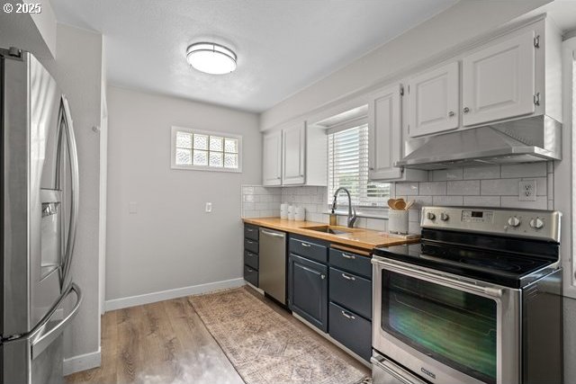 561 E Ridgeway Ave, Hermiston, OR 97838 - kitchen featuring stainless steel appliances, under cabinet range hood, white cabinetry, backsplash, and light wood finished floors