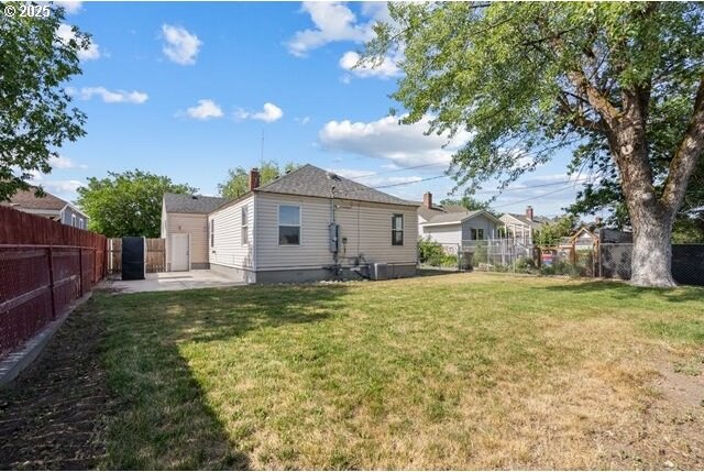 561 E Ridgeway Ave, Hermiston, OR 97838 - back of property featuring a fenced backyard, a patio area, and a chimney