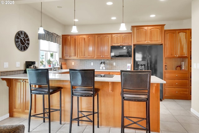 kitchen with black appliances, a peninsula, a sink, a breakfast bar, and recessed lighting