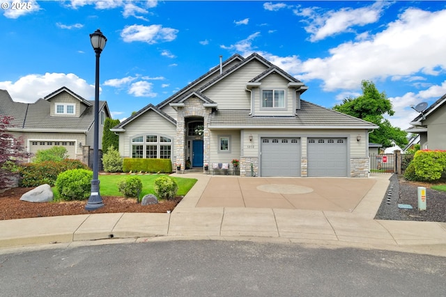 view of front of home with stone siding, concrete driveway, a gate, and an attached garage