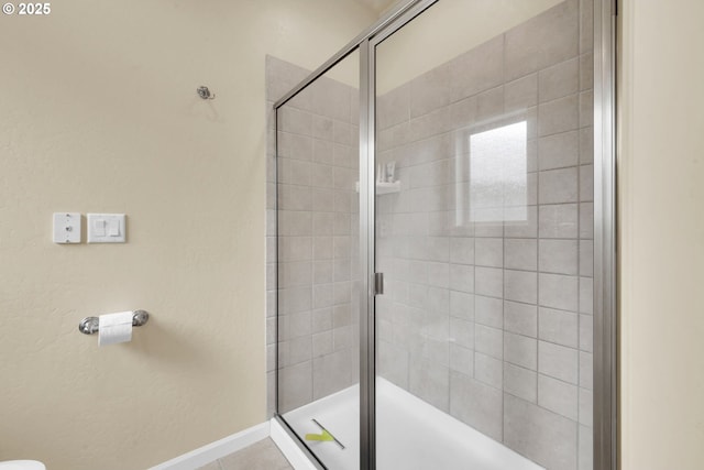 full bath featuring a shower stall and baseboards