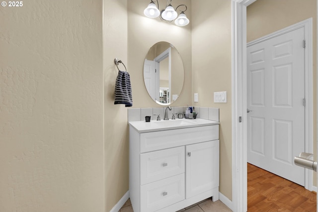 bathroom with vanity, baseboards, a chandelier, and a textured wall