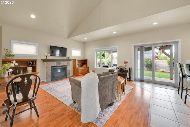living area featuring a fireplace, vaulted ceiling, recessed lighting, and light wood-type flooring