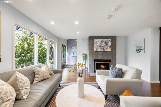 living room featuring baseboards, recessed lighting, wood finished floors, and a fireplace