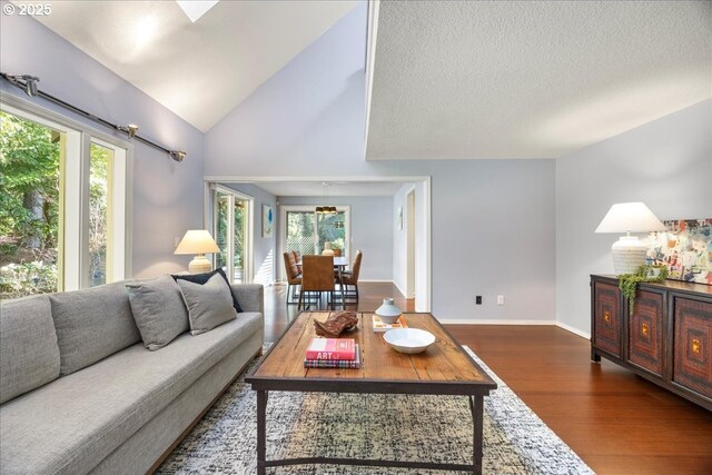 living area with lofted ceiling, baseboards, and wood finished floors
