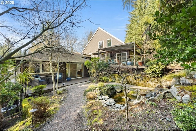 view of front of home featuring gravel driveway, a wooden deck, and a pergola