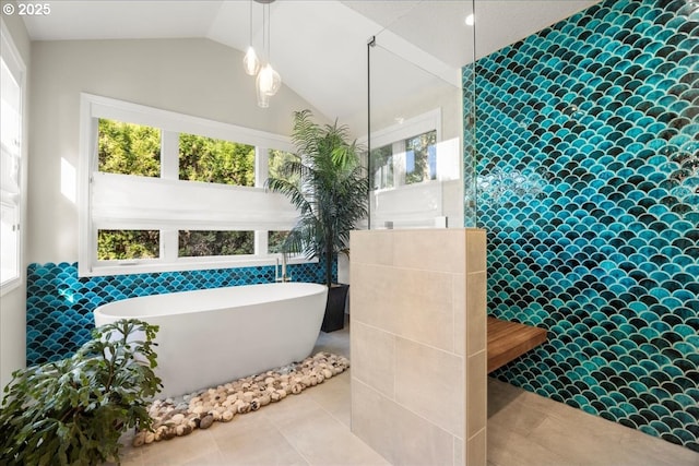 bathroom with tile walls, a freestanding tub, vaulted ceiling, walk in shower, and tile patterned floors