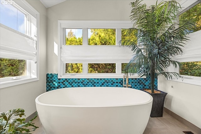 bathroom featuring tile patterned flooring, baseboards, and a soaking tub