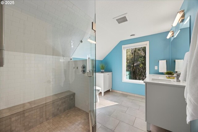 full bath featuring vanity, vaulted ceiling, a stall shower, tile patterned floors, and visible vents