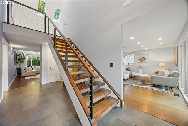 stairs with baseboards, recessed lighting, tile patterned flooring, and a high ceiling