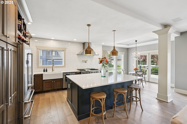 4706 NE 137th St, Vancouver, WA 98686 - kitchen with wall chimney range hood, ornate columns, appliances with stainless steel finishes, tasteful backsplash, and recessed lighting