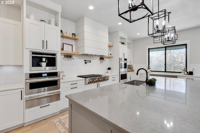 kitchen featuring light stone counters, hanging light fixtures, stainless steel appliances, backsplash, and white cabinets