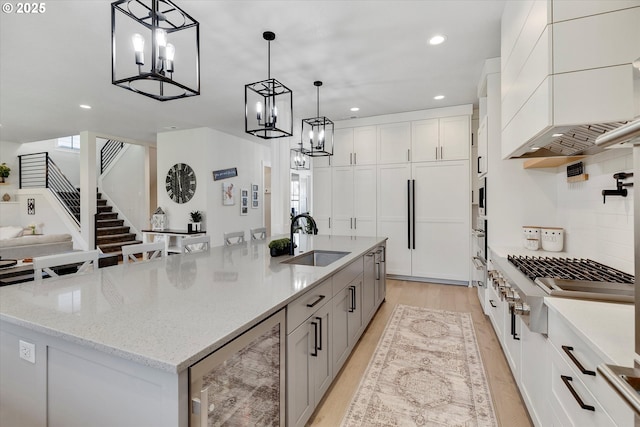 kitchen featuring decorative light fixtures, white cabinets, a spacious island, and sink