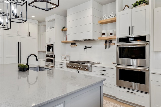 kitchen with sink, stainless steel appliances, white cabinetry, and light stone countertops