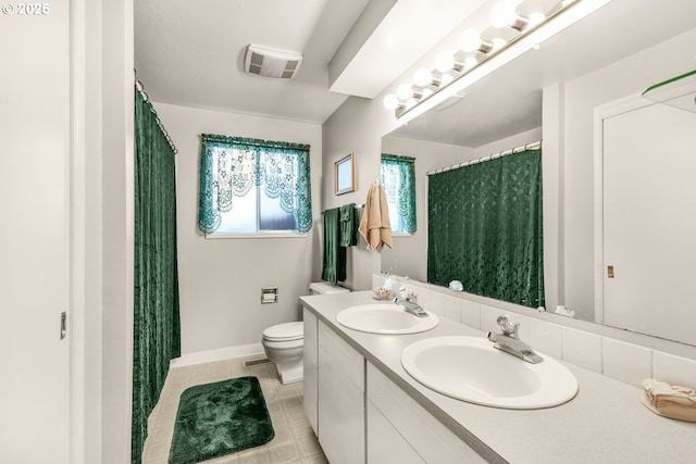 bathroom with toilet, double vanity, tile patterned floors, and baseboards
