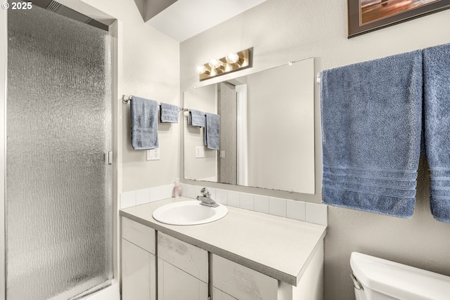 bathroom with toilet, a stall shower, and vanity