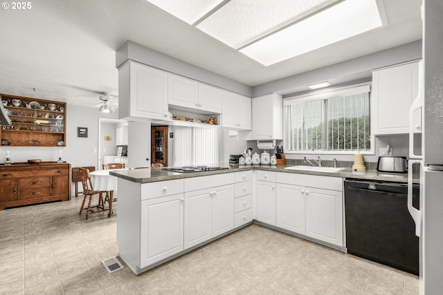 kitchen with black dishwasher, a sink, a peninsula, cooktop, and white cabinets