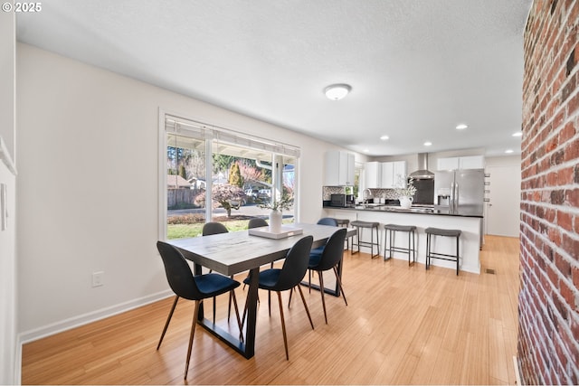 dining room featuring sink, a textured ceiling, and light hardwood / wood-style floors